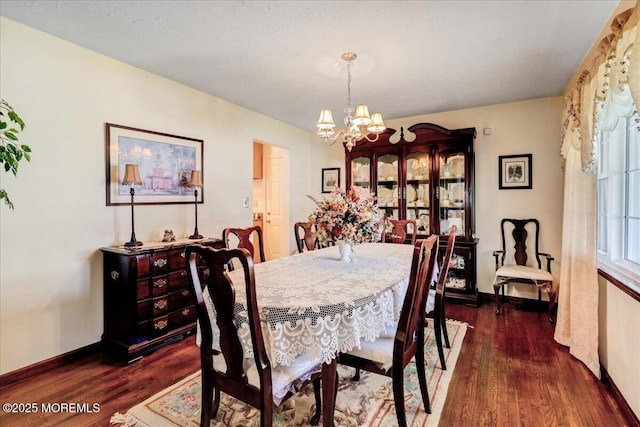 dining area featuring an inviting chandelier, baseboards, and dark wood-style floors