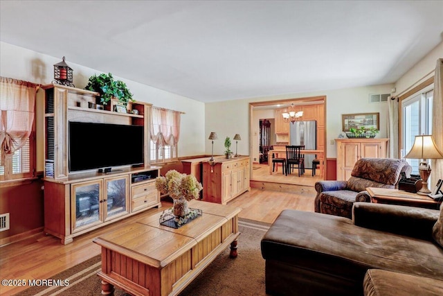 living room with visible vents, light wood-style flooring, and a notable chandelier