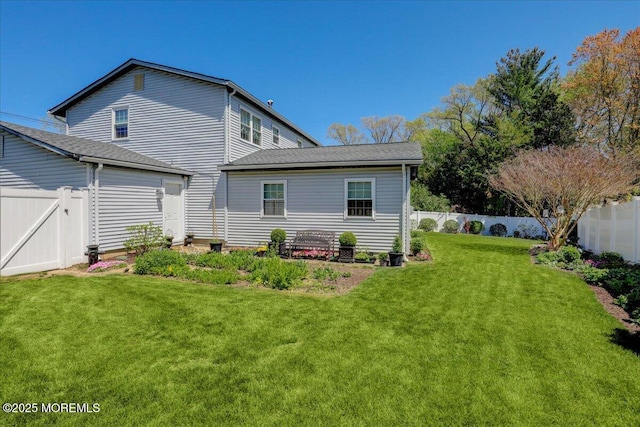 back of house with a lawn and a fenced backyard