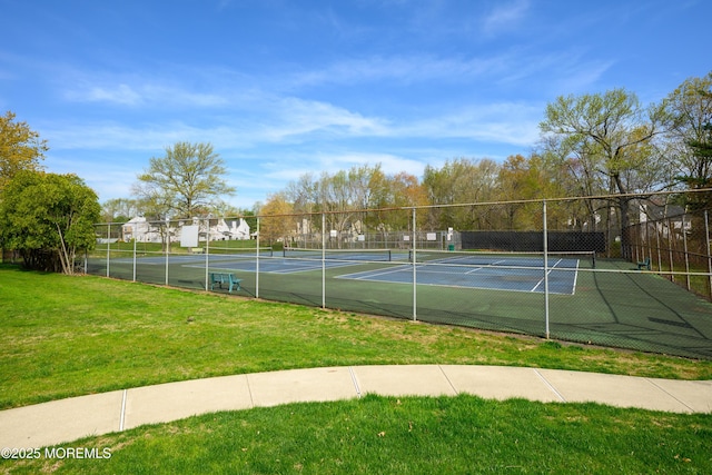 view of sport court with a lawn and fence