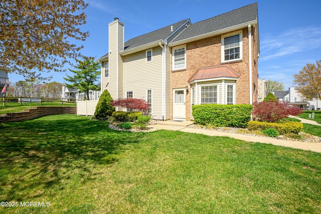 back of property with a lawn, brick siding, fence, and a chimney
