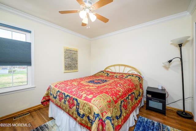 bedroom featuring visible vents, crown molding, wood finished floors, baseboards, and a ceiling fan