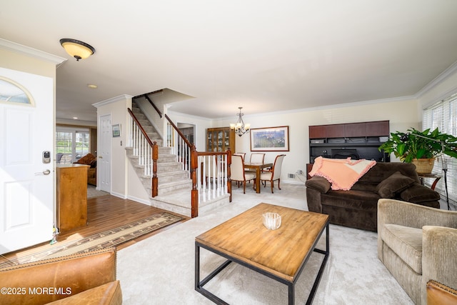 living area featuring plenty of natural light, ornamental molding, a chandelier, and stairway