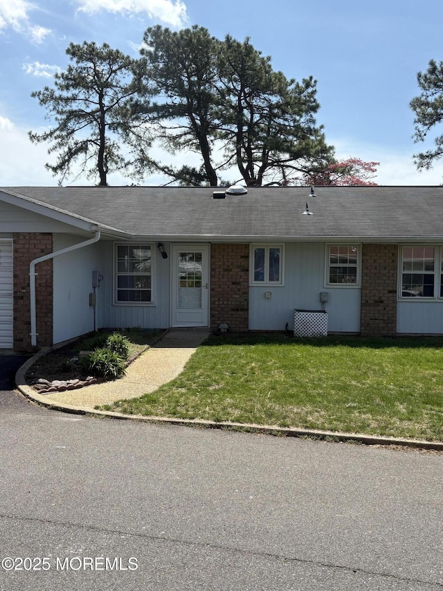 ranch-style home featuring a front yard and brick siding