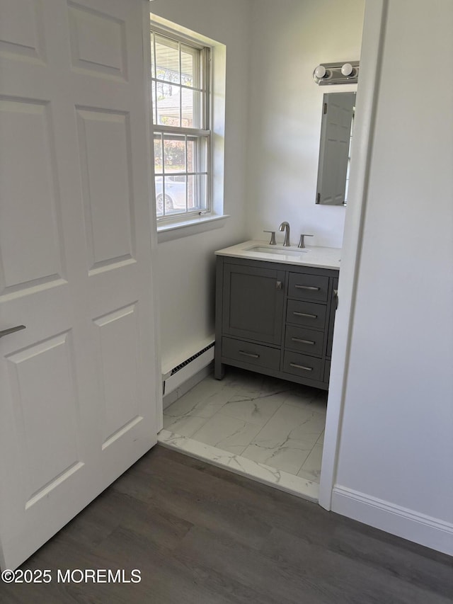 bathroom with marble finish floor, vanity, a baseboard heating unit, and baseboards