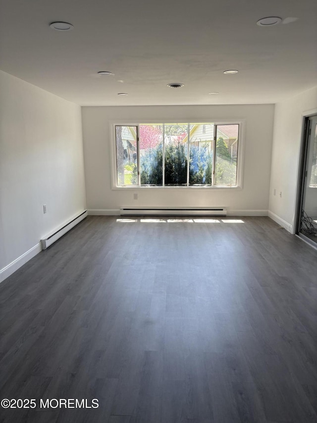empty room with a baseboard radiator, a healthy amount of sunlight, baseboard heating, and baseboards