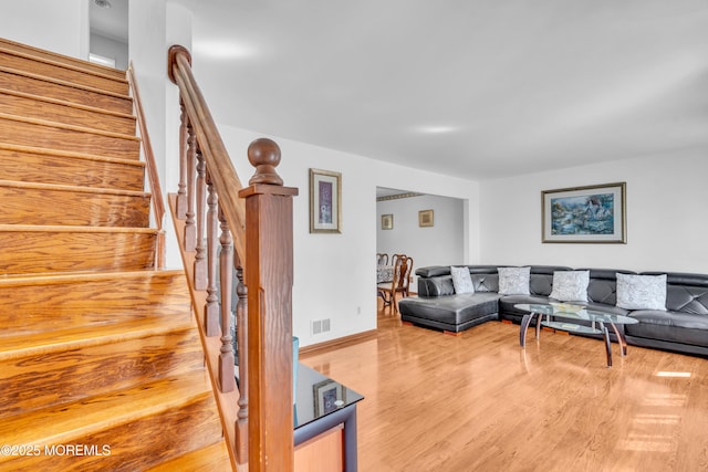 living room with visible vents, stairway, wood finished floors, and baseboards