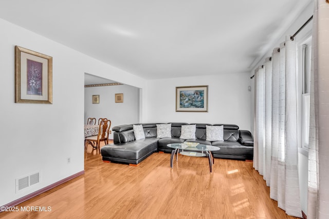 living room featuring visible vents, light wood-style flooring, and baseboards