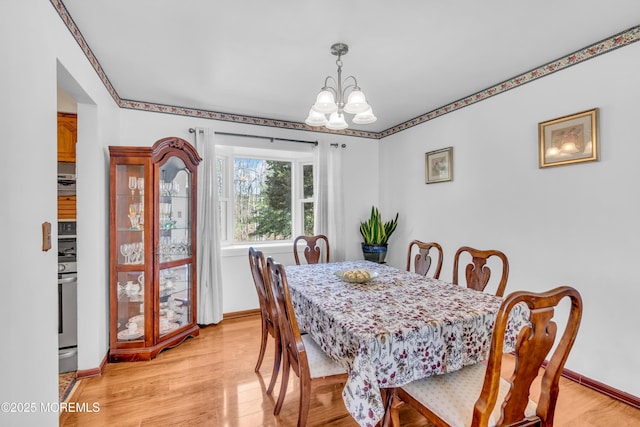 dining space featuring a chandelier, baseboards, and light wood-style floors