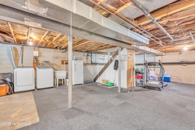 unfinished basement with independent washer and dryer, concrete block wall, and a sink