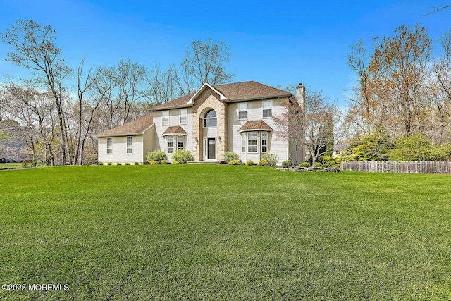view of front of house featuring a chimney, fence, and a front yard
