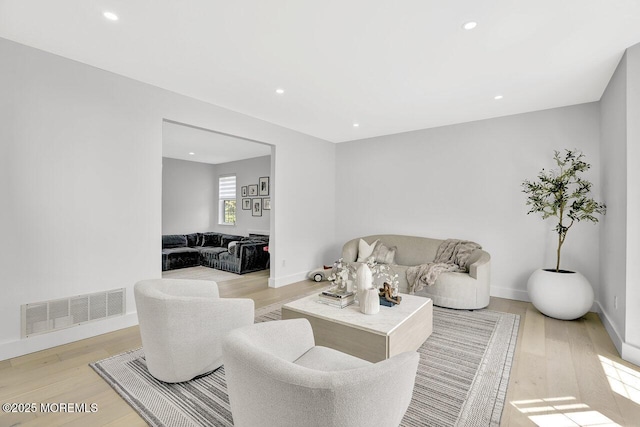 living area with recessed lighting, baseboards, visible vents, and light wood finished floors