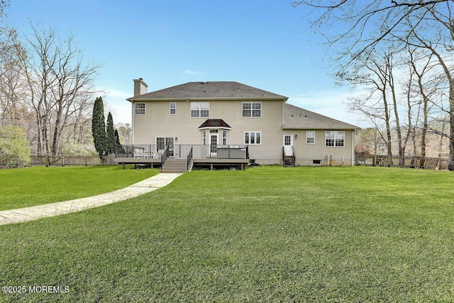 rear view of house with a yard, a deck, fence, and a chimney