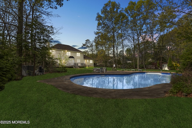 outdoor pool with a wooden deck and a yard