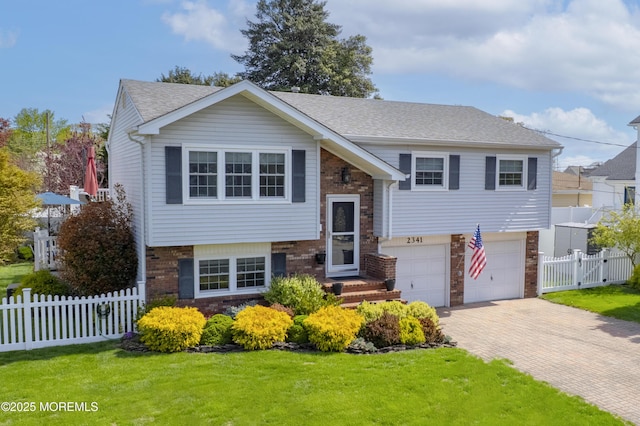 split foyer home featuring a front lawn, fence, brick siding, a garage, and decorative driveway