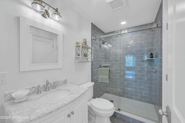 bathroom featuring toilet, visible vents, a shower stall, and vanity