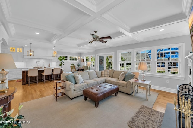 living room with a ceiling fan, light wood finished floors, and coffered ceiling