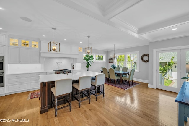 kitchen with a notable chandelier, light countertops, recessed lighting, white cabinetry, and glass insert cabinets
