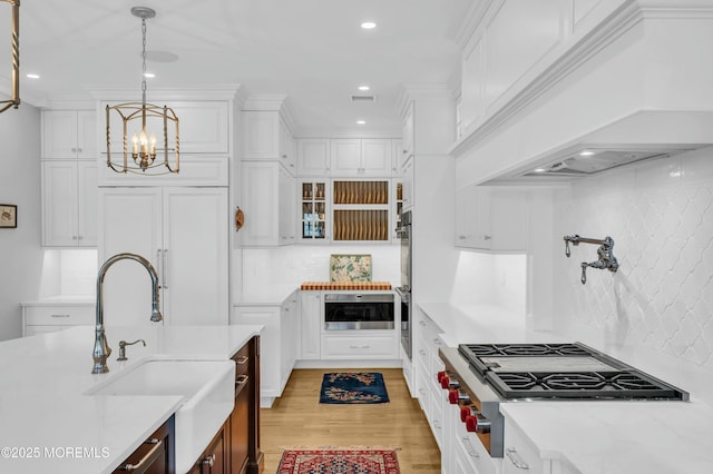 kitchen featuring stainless steel appliances, a notable chandelier, white cabinetry, and a sink