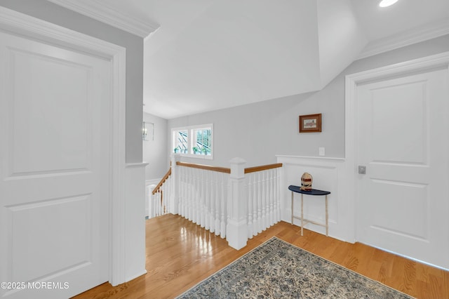 stairs with crown molding, lofted ceiling, and wood finished floors
