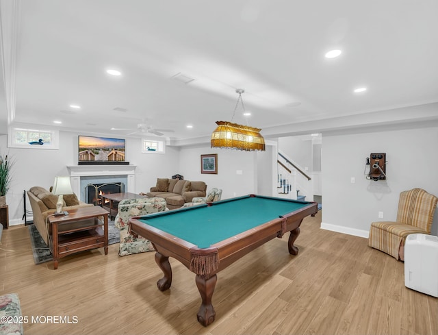 recreation room featuring a warm lit fireplace, ceiling fan, light wood-style floors, pool table, and baseboards