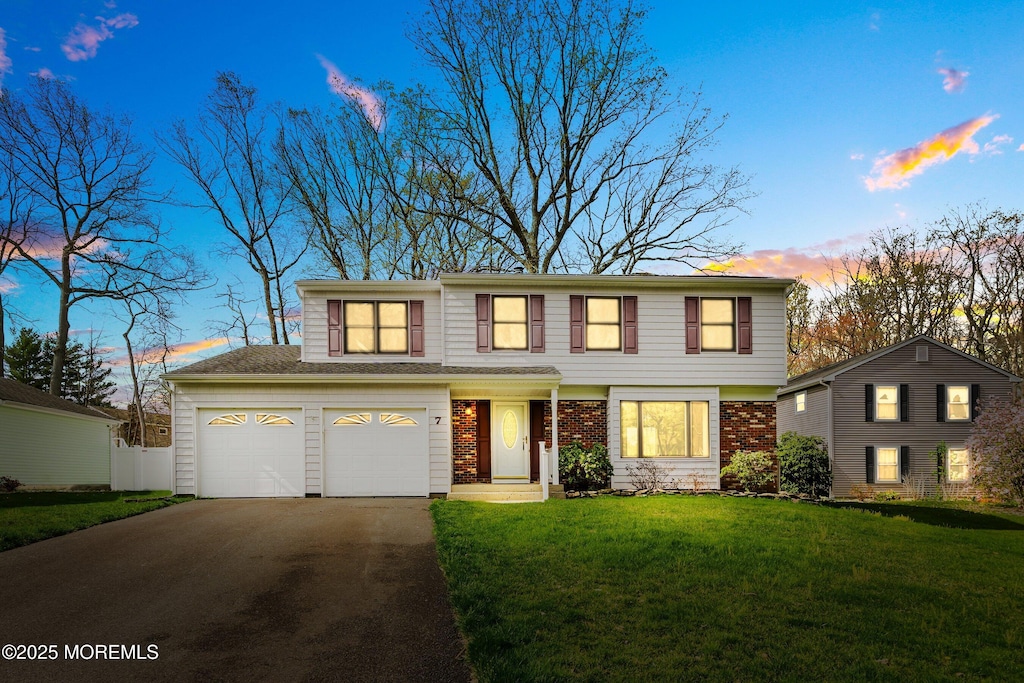 view of front of house featuring brick siding, aphalt driveway, and a front yard