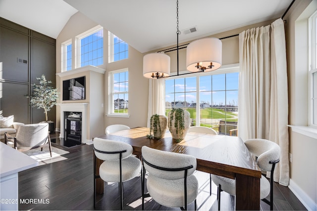 dining room with baseboards, a high end fireplace, visible vents, and dark wood-type flooring