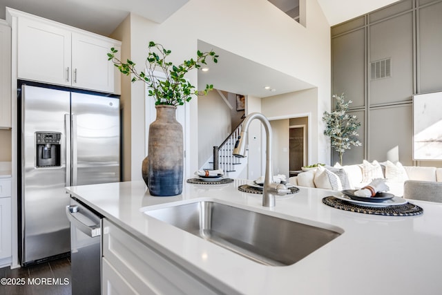 kitchen with a sink, stainless steel appliances, white cabinetry, visible vents, and light countertops