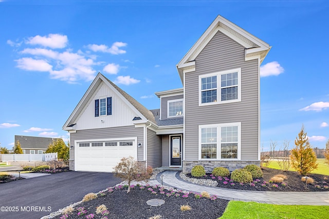 traditional-style home featuring stone siding, a garage, fence, aphalt driveway, and board and batten siding