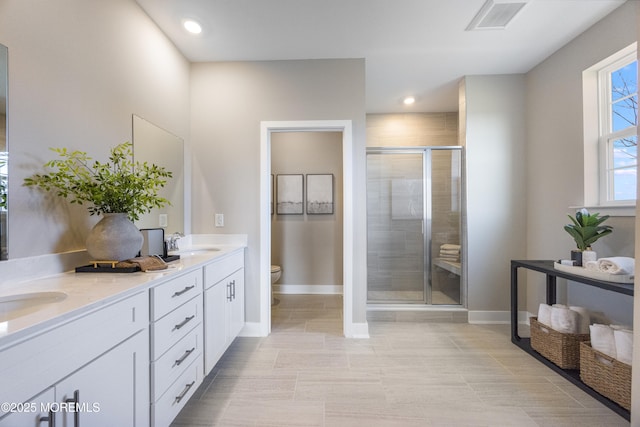 bathroom with toilet, baseboards, visible vents, a sink, and a shower stall