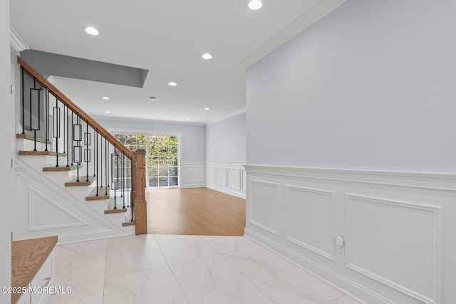 interior space featuring a decorative wall, wainscoting, marble finish floor, ornamental molding, and recessed lighting
