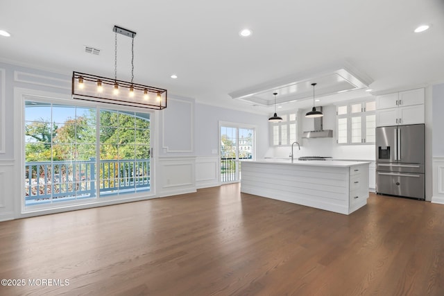 kitchen featuring a decorative wall, glass insert cabinets, a tray ceiling, light countertops, and stainless steel refrigerator with ice dispenser