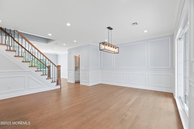 unfurnished dining area with crown molding, stairs, and a decorative wall