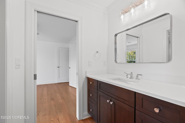 bathroom featuring baseboards, wood finished floors, vanity, and ornamental molding