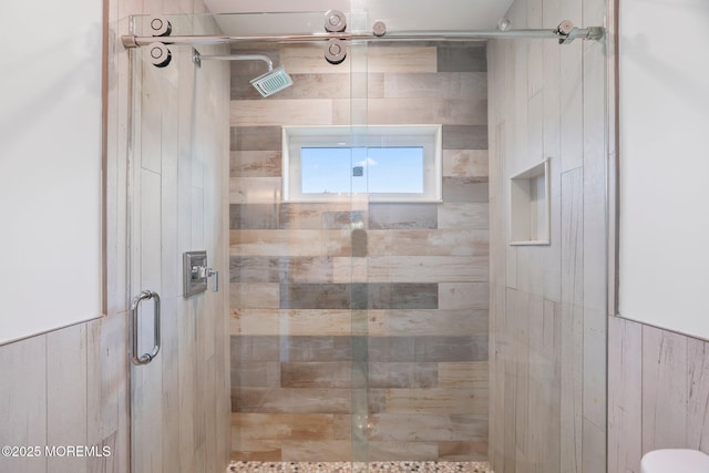 bathroom featuring wooden walls and a stall shower