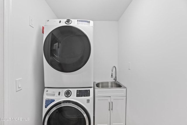 laundry room with cabinet space, stacked washer and dryer, and a sink