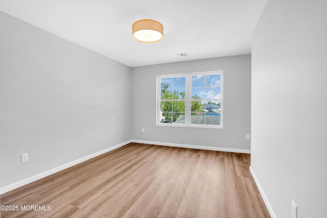 spare room featuring baseboards, visible vents, and wood finished floors