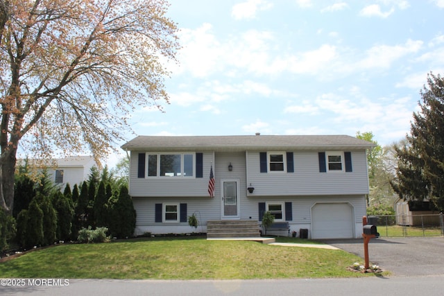 split foyer home featuring an attached garage, fence, driveway, and a front lawn