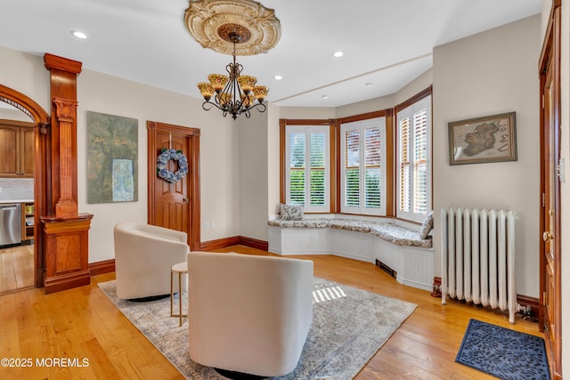 44 Irving Pl, Red Bank, NJ 07701 - living area featuring radiator heating unit, a chandelier, light wood-style floors, and decorative columns