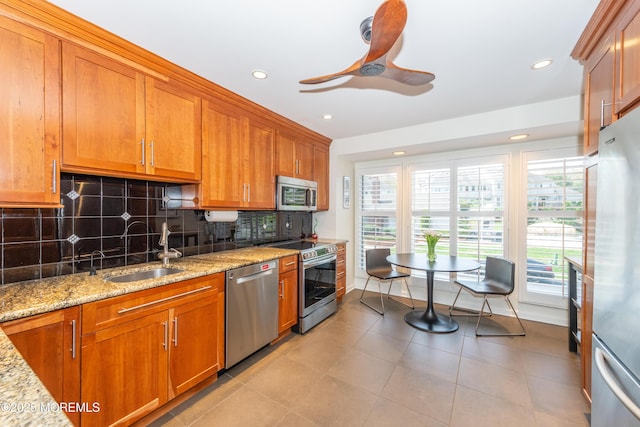 kitchen featuring a sink, appliances with stainless steel finishes, brown cabinets, and a healthy amount of sunlight