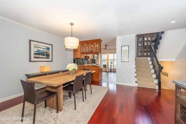 dining area with baseboards, stairs, crown molding, and dark wood-style floors