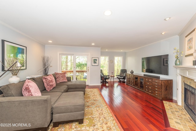 living area featuring a tile fireplace, wood finished floors, baseboards, ornamental molding, and recessed lighting
