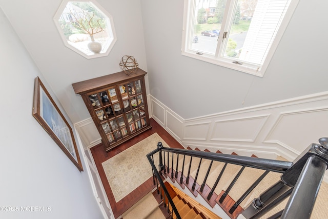 staircase featuring wainscoting and a decorative wall
