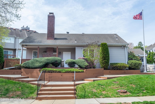view of front of home featuring roof with shingles, a chimney, and a front lawn