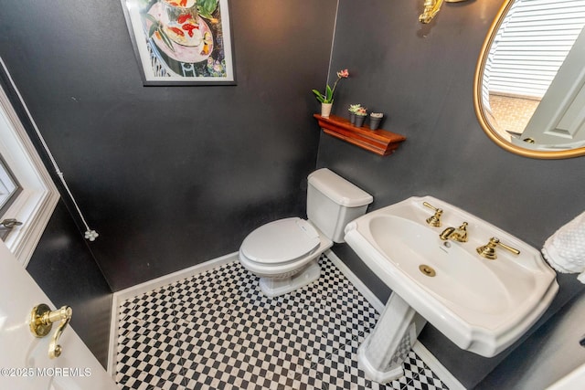 bathroom with toilet, baseboards, a sink, and tile patterned floors