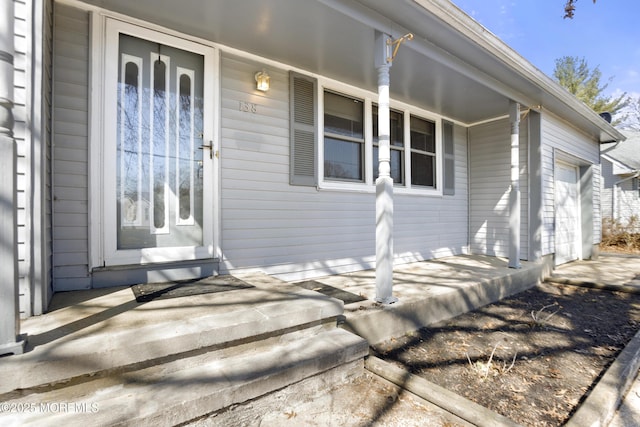 doorway to property featuring an attached garage and covered porch