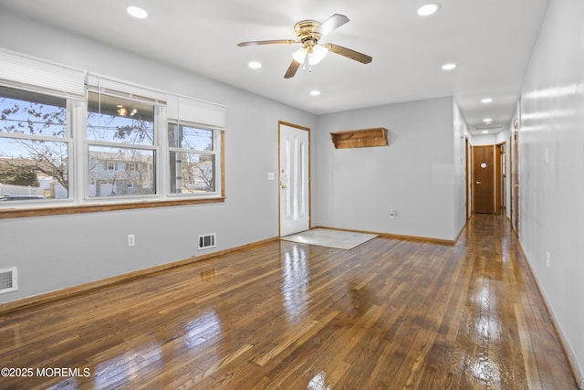 interior space with hardwood / wood-style flooring, baseboards, a ceiling fan, and visible vents