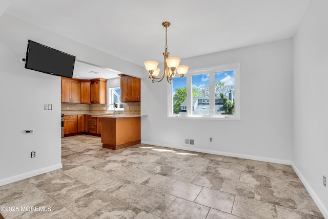 kitchen featuring a chandelier, baseboards, light countertops, and plenty of natural light