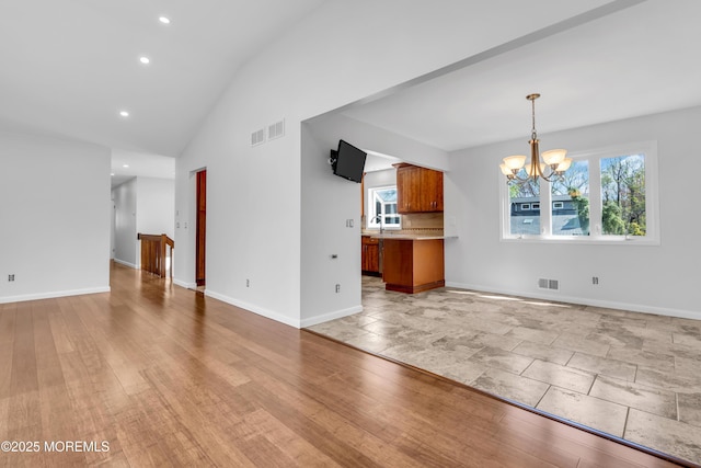 interior space with a notable chandelier, recessed lighting, baseboards, visible vents, and a sink