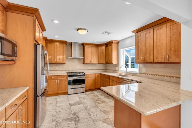 kitchen featuring visible vents, a sink, wall chimney exhaust hood, tasteful backsplash, and appliances with stainless steel finishes